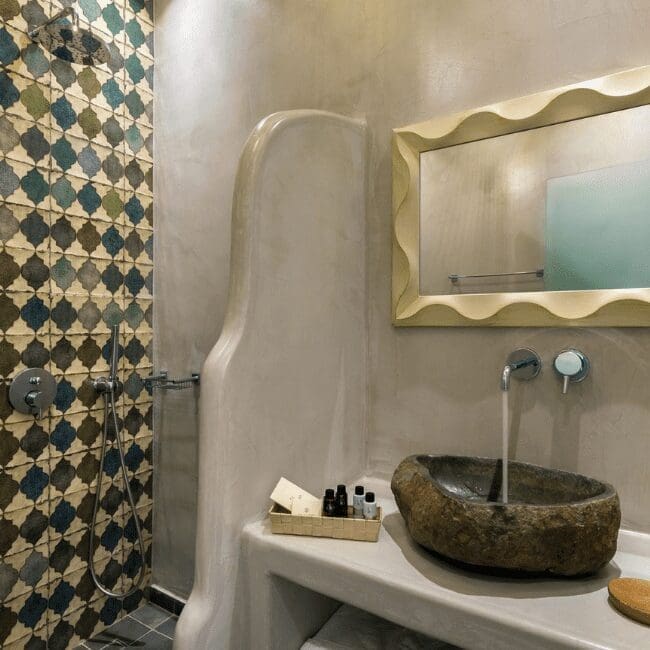 Bathroom with patterned shower tiles and a stone basin in the Suite with Pool View