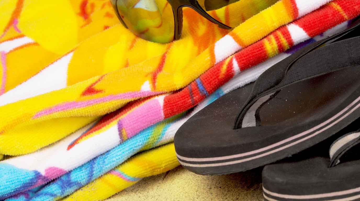 Beach towel, sunglasses and flip-flops on sand, the essentials for a day at Exo Gialos beach