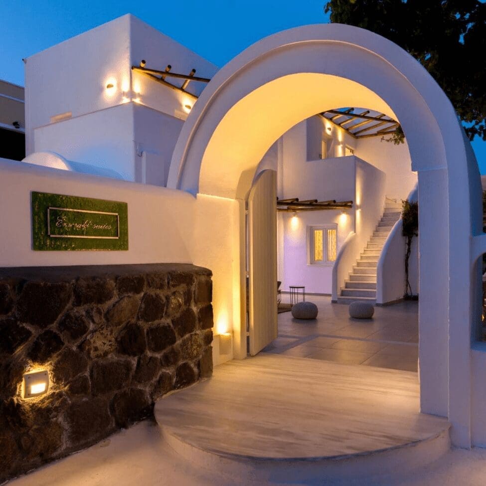 Stone archway entrance to Emerald Collection Suites lit at twilight