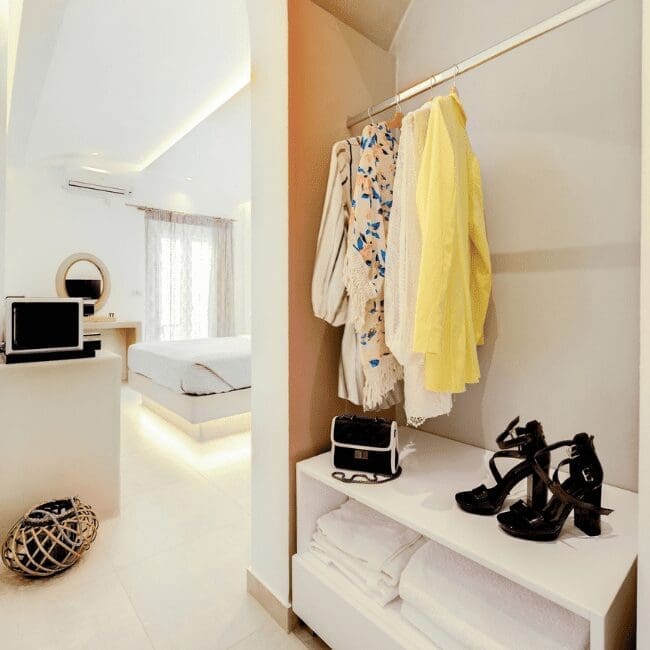 Standard Suite open wardrobe with clothing, heels and folded towels