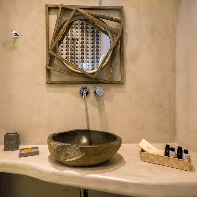Standard Suite bathroom with a stone basin and sculptural wood-framed mirror