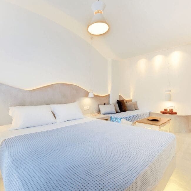 Double bedroom with a curved headboard and soft lighting in the Suite with Pool View