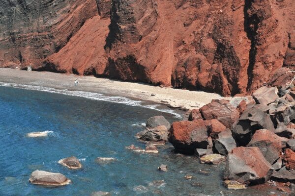Red Beach framed by towering red volcanic cliffs and clear water near Akrotiri, Santorini